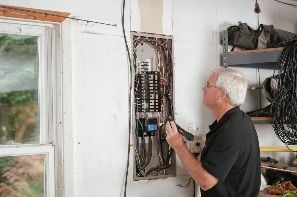 Eletricista revisando quadro de disjuntores em atendimento residencial em Moema, São Paulo