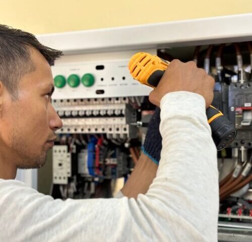 Eletricista realizando reparo em painel elétrico