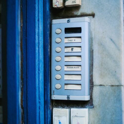Painel de interfone com múltiplos botões em entrada residencial